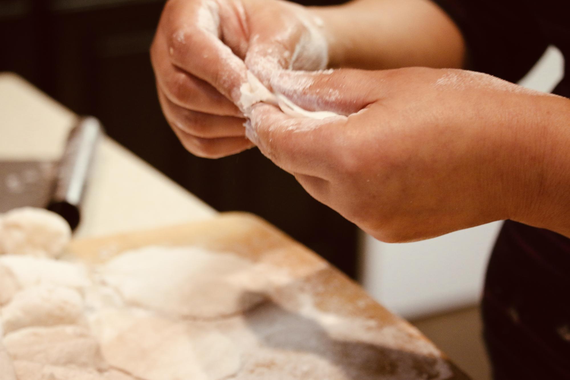 Close-up of hands kneading dough with flour